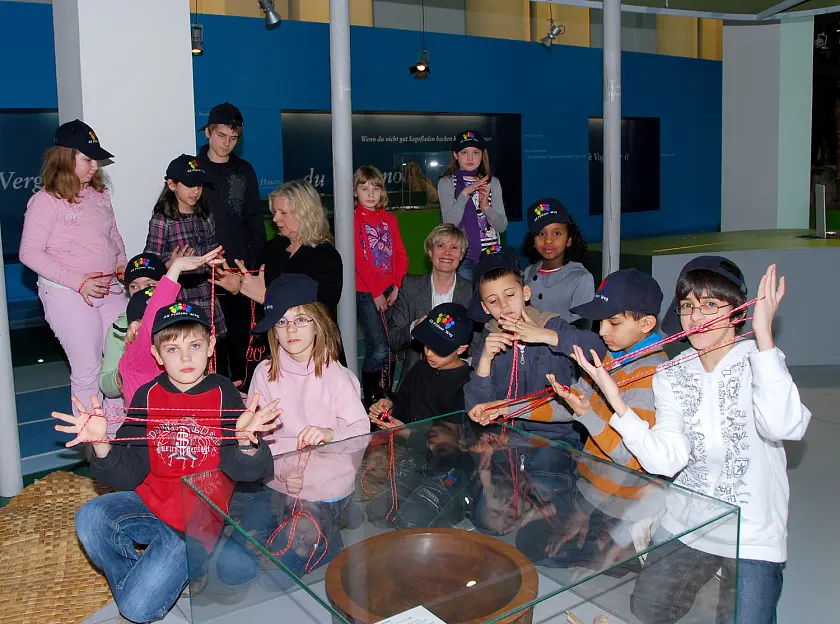 Dagmar  von Blacha (Mitte links), Referatsleiterin beim Senator für Kultur, besucht Kinder der Grundschule Pfälzer Weg in der Ozeanien-Abteilung des Übersee-Museums. Die Schüler demonstrieren ihr und Gabriele Müller, Geschäftsführerin des Übersee-Museums, Fadenspiele, die sie während einer Führung gelernt haben. Der Klassenausflug wurde ermöglicht durch den Verein „Museum macht Schule“. 