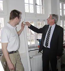 Bürgermeister Jens Böhrnsen lässt sich von Tischler Torben Drischel die Sanierungsarbeiten an den Fenstern erläutern