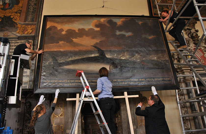 Zur Hängung des Gemäldes werden alle Hände gebraucht.