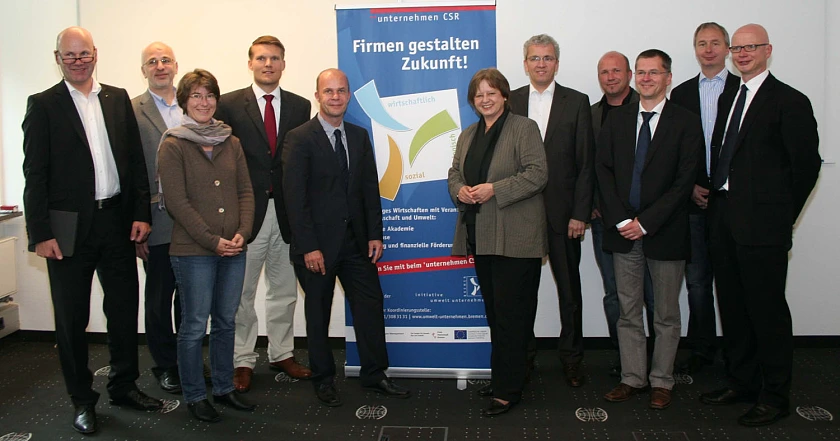 v.l.n.r. neben dem Banner: Kick-off von 'unternehmen CSR': Umweltstaatsrätin Gabriele Friderich mit den Projektinitiatoren Martin Schulze von der ‘initiative umwelt unternehmen‘ und Prof. Dr. Georg Müller-Christ, Universität Bremen, mit den Unternehmen der Startergruppe
