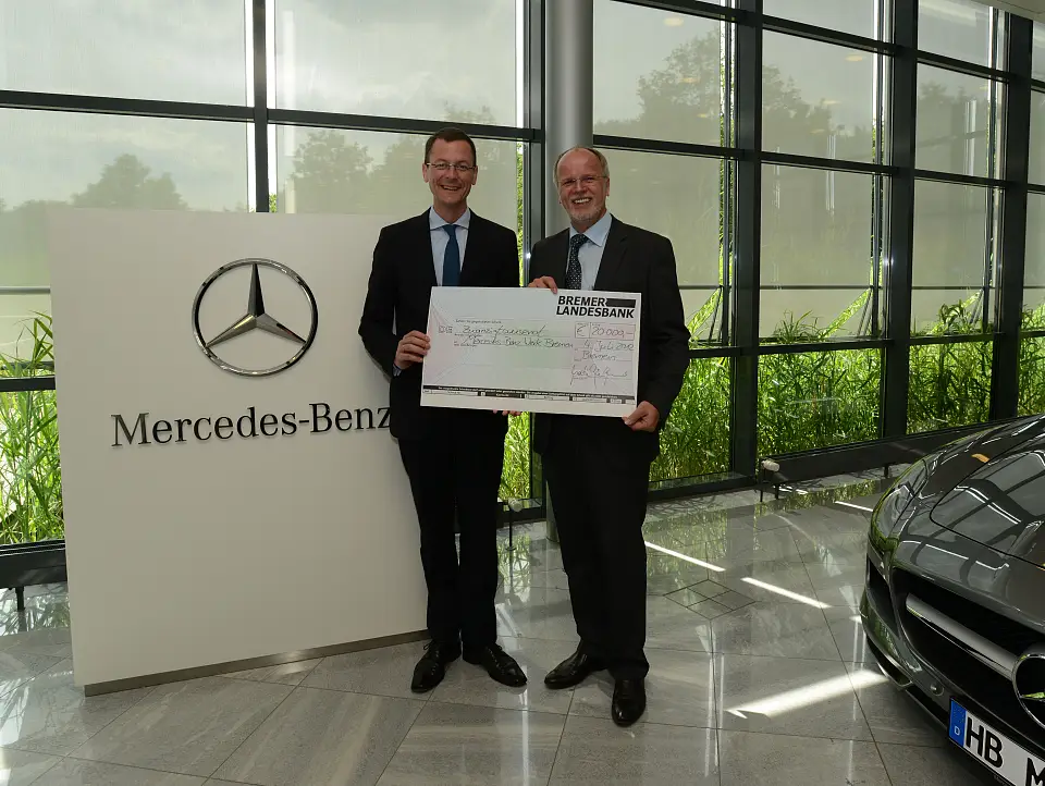 Senator Günthner überreicht den Scheck zum Preis Betriebliches Eingliederungsmanagement an Mercedes-Werksleiter Andreas Kellermann (li.)