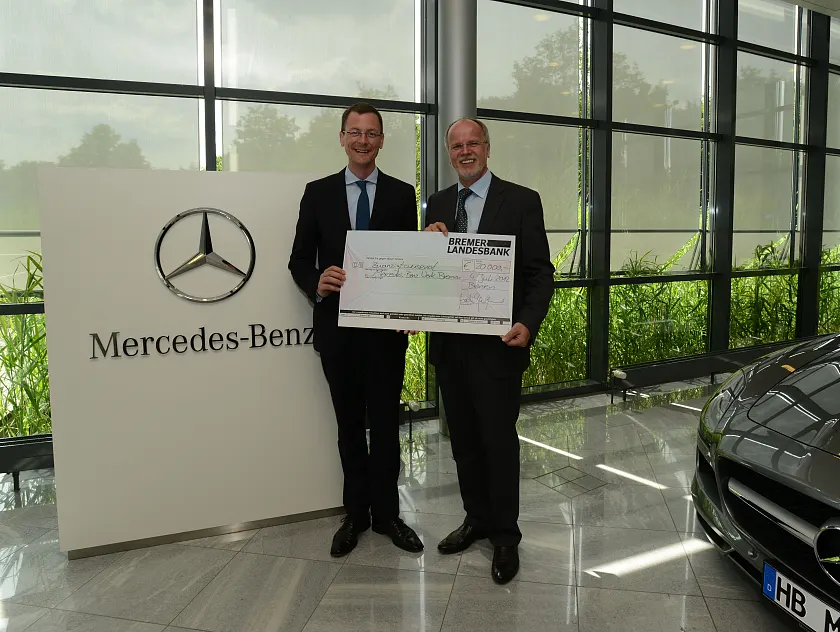 Senator Günthner überreicht den Scheck zum Preis Betriebliches Eingliederungsmanagement an Mercedes-Werksleiter Andreas Kellermann (li.)