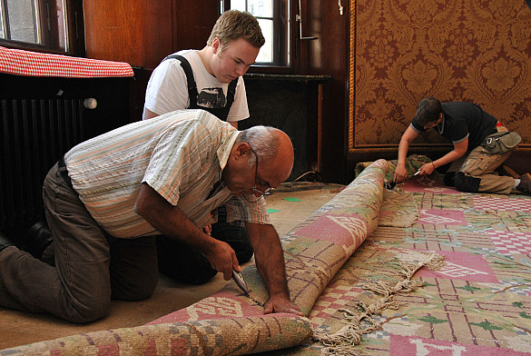 Ceyhan Ates und Patrick Elfers (von links) von der Firma Gleue beim Zerschneiden des alten Teppichs im Senatssaal