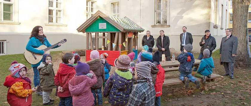 Man sieht es, sie freuen sich: Lauter kleine Igel, Elefanten, Frösche, Pinguine - so heißen die Kindergruppen in der Kita am Klinikum Bremen Mitte, an der Gitarre begleitet von ihrer Erzieherin Kathrin Warnicke. Die Namen der erwachsenen Herren weiter rechts: Andreas Meyer, Geschäftsführer der Kreishandwerkerschaft und der HandWERK gGmbH, Joachim Feldmann, Hauptgeschäftsführer der Handwerkskammer, Peter Brandt, technischer Leiter des Kompetenzzentrums der Handwerkskammer HandWERK gGmbH, Hans- Günter Schwalm, Fachberater und Partizipationsexperte bei KiTa Bremen, und der Präses der Handwerkskammer,  Markus Mertsch, Hauptgeschäftsführer der Handwerkskammer (von links)