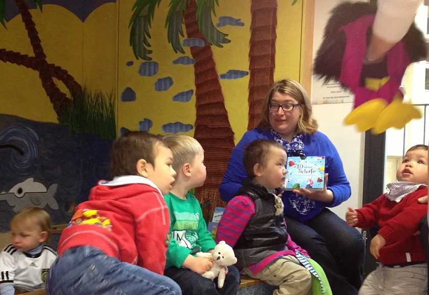 Senatorin Anja Stahmann auf einer Lese-Insel in der Stadtbibliothek Am Wall mit einigen Kindern aus der deutsch-chinesischen Kita „Drachenkinder“