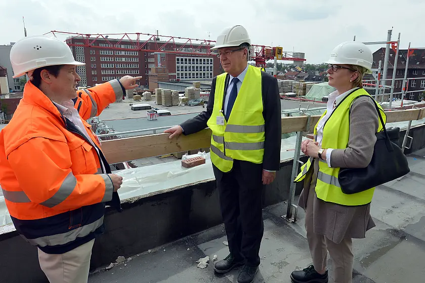 Auf dem Dach des Rohbaus berichtet Birte-Jay Thielemann, Bauplanerin aus der Abteilung Besonderes Projektmanagement der Gesundheit Nord (links), Bürgermeister Jens Böhrnsen und Jutta Dernedde, medizinische Geschäftsführerin der Gesundheit Nord, vom aktuellen Stand der Arbeiten