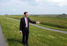 Senator Günthner auf dem Deich, im Hintergrund ist der neue Tidepolder zu sehen