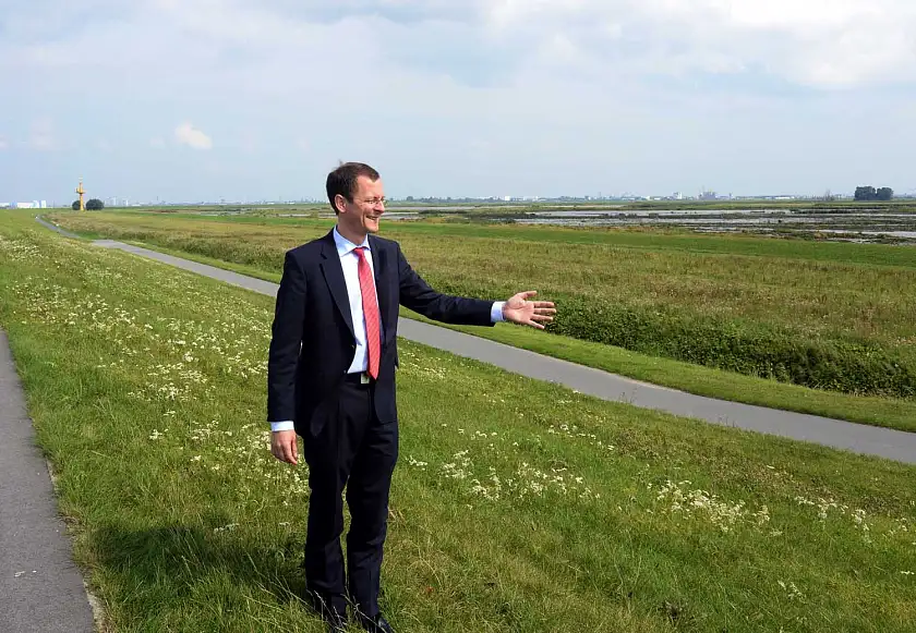 Senator Günthner auf dem Deich, im Hintergrund ist der neue Tidepolder zu sehen