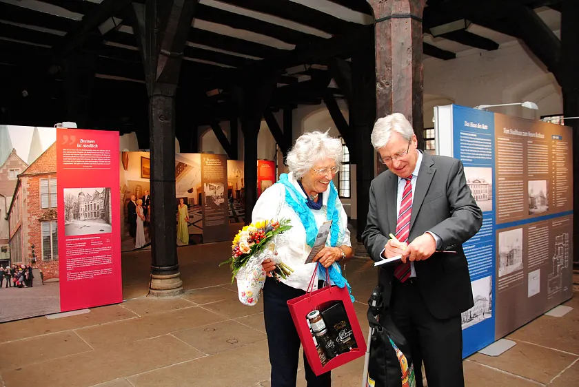 Bürgermeister Jens Böhrnsen signiert für die 70.000. Besucherin ein Buch über das Neue Rathaus
