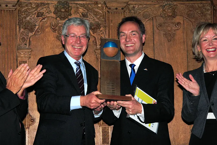 Bremens Bürgermeister Jens Böhrnsen überreicht dem Rostocker Senator Holger Matthäus den Wanderpokal und gratuliert zum Titel "Hauptstadt des Fairen Handels 2013"]