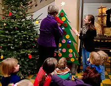 Ingelore Rosenkötter, Bürgerschaftsabgeordnete und Initiatorin der Adventskalenderaktion, hilft einem Kind der Hemelinger Kinderkrippe beim Öffnen des Türchens