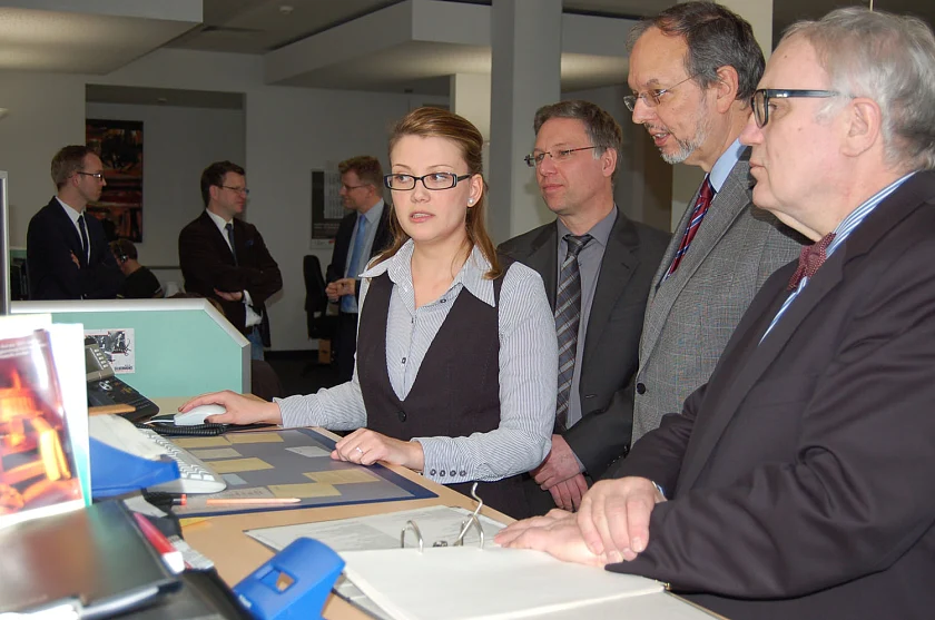 Veronika Salamacha, Verwaltungsangestellte und stellvertretende Teamleiterin beim Bürgertelefon Bremen, erläutert Finanz-Staatsrat Henning Lühr (re.), Ministerialdirektor Dr. Georg Thiel vom Bundesinnenministerium (2. v. r.) und Thomas Elsner, Leiter des Bürgertelefons Bremen, die Arbeitsabläufe und Anforderungen in der telefonischen Beratung