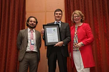 Isabelle Ryckbost, Generalsekräterin der ESPO, und  Antonis Michael, leitender Referent der ESPO übergeben die Urkunde an Jochen Kreß, Mitarbeiter beim Senator für Wirtschaft, Arbeit und Häfen.