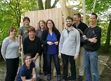 Bau eines Gartenhäuschens. Das Foto mit allen Teilnehmenden zeigt: Kniend Erzieherin Anke Krüger, nächste Reihe: Erzieherin Gaby Stadtlander (ganz links), Dorothea Staiger (aus dem Stab der Senstorin); Senatorin Anja Stahmann; David Lukaßen (aus dem Stab der Senatorin), Martin Wind, Abteilungsleiter „zentrale Dienste“  im Sozialressort (gaznz rechts mit Brille), Dipl. Ing Frank Zarsteck von ghepetto, Ute Lankenau (Leiterin des Kinder- und Familienzentrums), Rolf Diener, Jugendamtsleiter