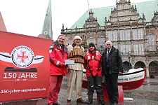Mit großen Schritten gehen die Seenotretter einem besonderen Jubiläum entgegen: Am 29. Mai 2015, in einem Jahr, wird die Deutsche Gesellschaft zur Rettung Schiffbrüchiger (DGzRS) 150 Jahre alt. Der ehrenamtliche DGzRS-Vorsitzer Gerhard Harder (l.) und Bremens Innensenator Ulrich Mäurer (r.) stellten das Jubiläumsprogramm und eine besondere Internetseite am 28.5.2014, auf dem Bremer Marktplatz vor. Mit dabei: Armin Meyer, Maschinist des Seenotkreuzers EISWETTE von der Station Nordstrand an der Westküste Schleswig-Holsteins, gekleidet wie die Seenotretter in früheren Zeiten, und Christoph Müller, freiwilliger Seenotretter auf dem Seenotrettungsboot KONRAD-OTTO von der Station Kühlungsborn in Mecklenburg-Vorpommern in moderner Sicherheitsausrüstung.
