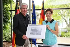 Jens Böhrnsen überreicht seiner Amtskollegin ein Gastgeschenk. Es handelt sich um eine historische Aufnahme aus dem Archiv des Deutschen Schiffahrtsmusuem in Bremerhaven. Zu sehen ist der Dampfer Saarbrücken, der unter der Flagge einer Bremer Reederei fuhr, im Hafen von Hongkong