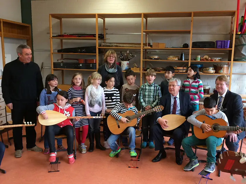 Bürgermeister Böhrnsen mit einem Saz-Instrument und Schülerinnen und Schüler einer Musikklasse der Schule Alt-Aumund. Mit im Bild Musikschul-Direktor Daniel Keding (re.), Schulleiterin Heike Ahrens und der Musiklehrer Firat Sönmetz