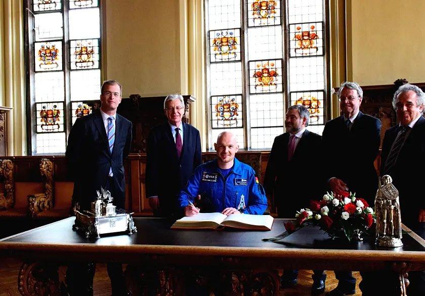 Mit Raumfahrt-Overall in der historischen Rathaushalle: Alexander Gerst beim Eintrag ins Goldene Buch. Mit im Bild (v.l.): Bart Reijnen, Airbus Defence & Space, Bürgermeister Böhrnsen, Hans-Georg Tschupke, Abteilungsleiter Innovation, Raumfahrt und Technologie bei der WfB Wirtschaftsförderung Bremen, Dr. Peter Vits, Raumfahrtkoordinator des Landes Bremen und Dr. Fritz Merkle, OHB Gruppe Bremen.