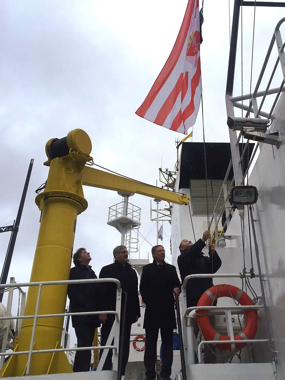 Zum Farewell hissen Kapitän Klaus Vogel, Bürgermeister Carsten Sieling, Bremerhavens OB Melf Grantz und Hans-Joachim Schnitger von der Bremischen Hafenvertretung die Bremer Speckflagge