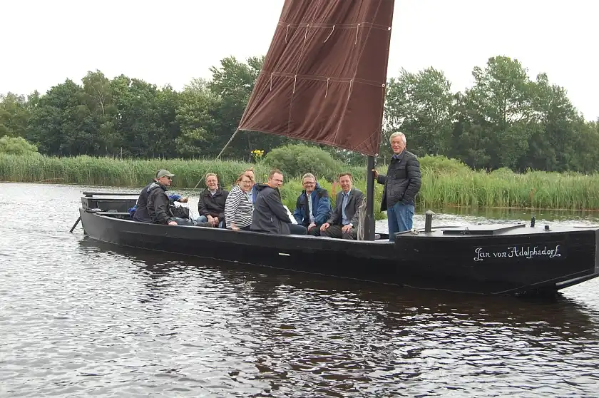 Bürgermeister Carsten Sieling (2. v. r.) und Landrat Bernd Lütjen (3. v. r.) mit Begleitung während der Torfkahnfahrt; mit im Bild: Ortsamtsleiter/Blockland Heinrich Schumacher (stehend)
