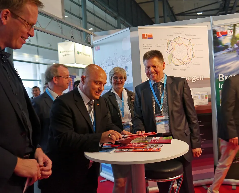 Senator Dr. Joachim Lohse (re.) zeigt Staatssekretär Rainer Bomba (mi.) den Messestand des Bremer Verkehrsressorts. Mit dabei der Leiter der Verkehrsabteilung Gunnar Polzin (vorne l.), Ministerialdirigent Dr. Stefan Krause (2. Reihe li.) und Amtsleiterin Brigitte Pieper (2. Reihe re.)