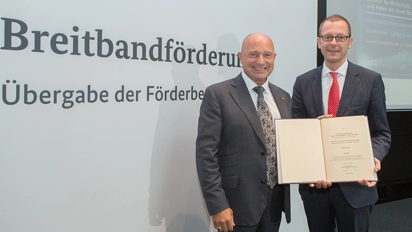 Rainer Bomba (links), Staatssekretär im Bundesministerium für Verkehr und digitale Infrastruktur überreicht den Förderbescheid an Martin Günthner (rechts), Senator für Wirtschaft, Arbeit und Häfen
