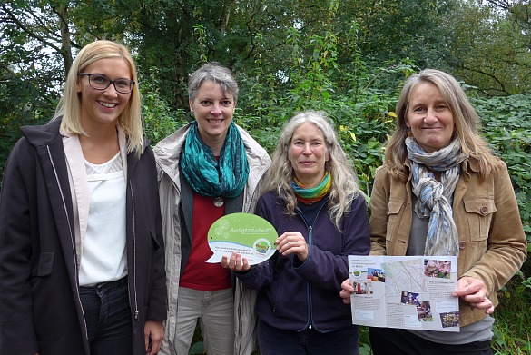 von links nach rechts. Sarah Kettler, Dr. Ulrike Christiansen, Doris Petersson, Sabine Schweitzer mit der Plakette "Ausgezeichnet" und dem neuen Walle-Flyer im wilden Grün des WUPP-Geländes.