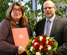 Senatorin Anja Stahmann übergibt Ahlrich Weiberg die Urkunde und einen Strauß Blumen
