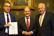 Der Verwaltende Vorsteher von Haus Seefahrt, Heiner Dettmer (rechts), und der 1. Schaffer und SWB-Vorstandsvorsitzende, Dr. Torsten Köhne (links), überreichen Hamburgs Erstem Bürgermeister Olaf Scholz die Einladung zur Schaffermahlzeit. 