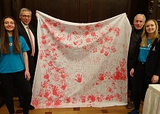 Bürgermeister Sieling und Christian Bruns, Leiter des Zukunftsbüros, zusammen mit zwei Unicef-Freiwilligen und dem Transparent der Aktion „Rote Hand“