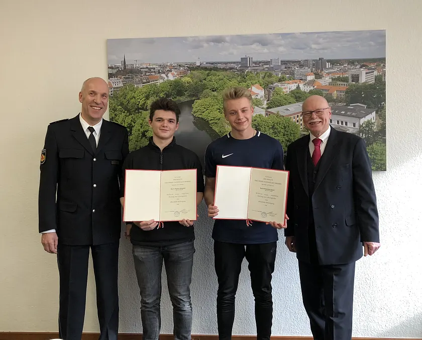 Innensenator Ulrich Mäurer (rechts) zeichnet Dominick Jansen (zweiter von rechts) und Markus Schneider (zweiter von links) durch eine öffentliche Belobigung aus. Jörg Meier (links) ist stellvertretender Leiter der Direktion Einsatz