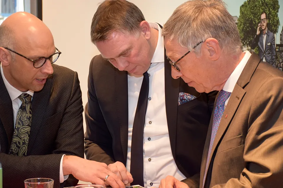 Jan-Peter Halves (links), Geschäftsführer der City Initiative und Jens Ristedt, Geschäftsführer und Inhaber der Ristedt City Modehaus GmbH, zeigen Bürgermeister Carsten Sieling die Broschüre zum 