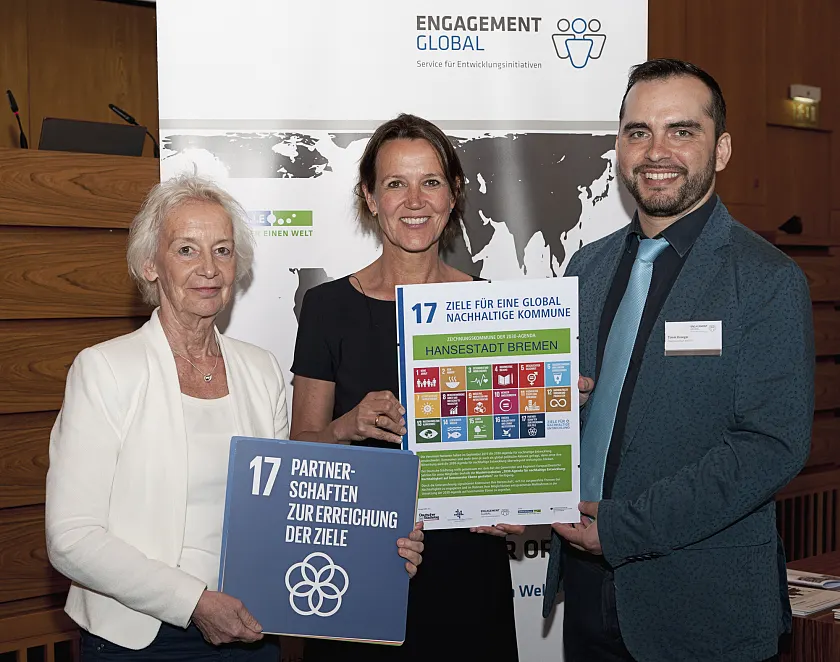 Sabine Drees (Deutscher Städtetag), Annette Turmann (SKEW) und Bremens Koordinator für kommunale Entwicklungspolitik, Timm Kroeger (BBEE), bei der Übergabe der Urkunde für Bremen als „Zeichnungskommune der 2030-Agenda-Resolution“.  |Foto: © Jo Hempel Photography