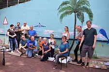 Künstler für einen Tag: Schon nach wenigen Stunden verströmte die neu bemalte Wand der Schule dank Innensenator Mäurer (hinten links im gelben Poloshirt) und seiner Kolleginnen und Kollegen eine fröhliche Sommerfrische