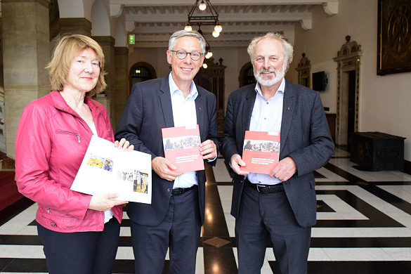 Heike Blanck, Bürgermeister Carsten Sieling und Helmut Weigelt nehmen die neue Broschüre in Augenschein