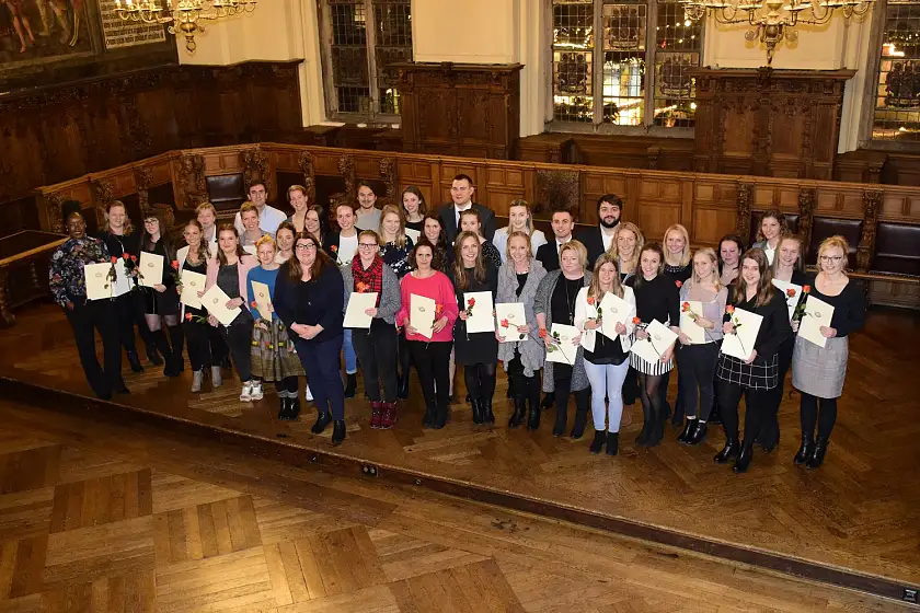 Senatorin Stahmann (Bildmitte) mit den Absolventinnen und Absolventen in den Gesundheitsfachberufen während der Feierstunde in der Oberen Rathaushalle
