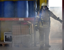 Ein Feuerwehrmann kommt aus einem verrauchten Raum. Seine Kleidung ist kontaminiert. 