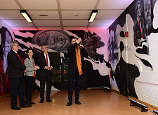 Künstler Peter Stöcker erläutert den Gästen, wie das Wandbild über das Leben Helmut Schmidts entstanden ist
