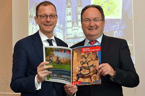 Wirtschaftssenator Martin Günthner und BTZ-Geschäftsführer Peter Siemering mit dem neuen Reisekatalog für Bremen