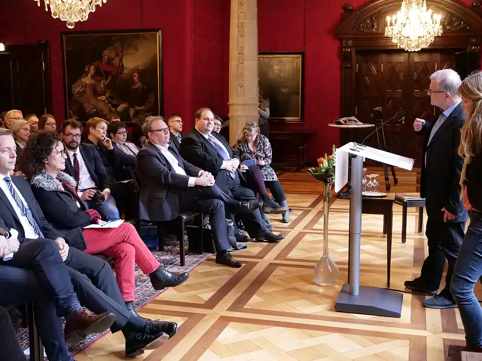 Die Laudatoren Uwe Frenzel und Anja Meyersiek (rechts im Bild) während der Feierstunde im Kaminsaal. Christian Humm (Mitte, vordere Reihe rechts) wurde die 