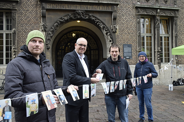 BeN-Geschäftsführer Christopher Duis (2.v.r.) zeigt Bürgermeister Bovenschulte einige Exemplare der gesammelten Postkarten