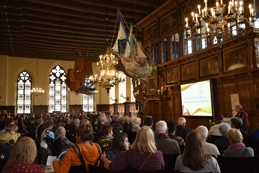 Regina Heygster (am Pult) spricht zu den Gästen der Veranstaltung „Frieden fängt klein an“ in der Oberen Rathaushalle