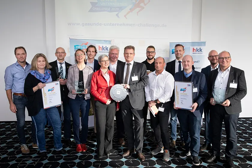 Bei der Preisverleihung: PerformaNord-Geschäftsführer Claus Suhling und Elke Berndt, zuständig für das Gesundheitsmanagement bei Performa Nord, mit einer Filmrolle (Bildmitte) als Symbol für den Ehrenpreis (Produktion eines Imagefilms). |Foto: Jörg Sarbach/hkk