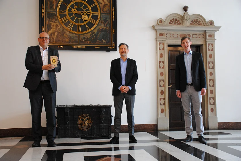 Mit Corona-gerechtem Abstand nahm Bürgermeister Bovenschulte die Nachbildung der ersten Jacobs Kaffeeverpackung aus den 30er Jahren von Luc Van Gorp (Mitte) in Empfang, rechts Unternehmenssprecher Dirk Friedrichs