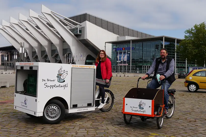 Nach einer kurzen Probefahrt auf der Bürgerweide übergibt Senatorin Stahmann das neue Lastenrad an Peter Valtink von den Suppenengeln