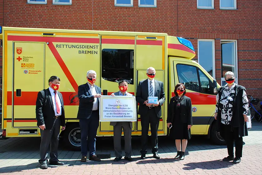 Lutz Müller (3v.r.), Hermann Schulte-Sasse (2.vl.) und Birgitt Rambalski (re.; Protokollchefin im Rathaus) nahmen die 6.500 Masken symbolisch von Kim Lien Ta (2.v.r.), Nguyen Van Hung (3.v.l.) und Nguyen Duc Thang (li.) entgegen