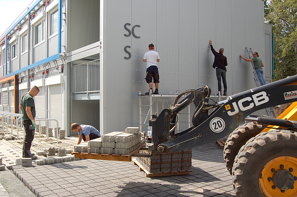 Endspurt am Interimsstandort der Schule Sodenmatt: Die Handwerker erledigen letzte Arbeiten an der Außenanlage und bringen den Schulschriftzug an der Fassade an. 
