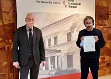 Innensenator Ulrich Mäurer (links) gratuliert Carlos Campos Serna aus Mexiko zur Einbürgerung.