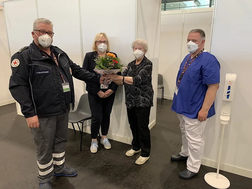 Frau Witte bekommt von Beschäftigten im Impfzentrum einen Blumenstrauß überreicht. Foto: Pressestelle Gesundheitsressort