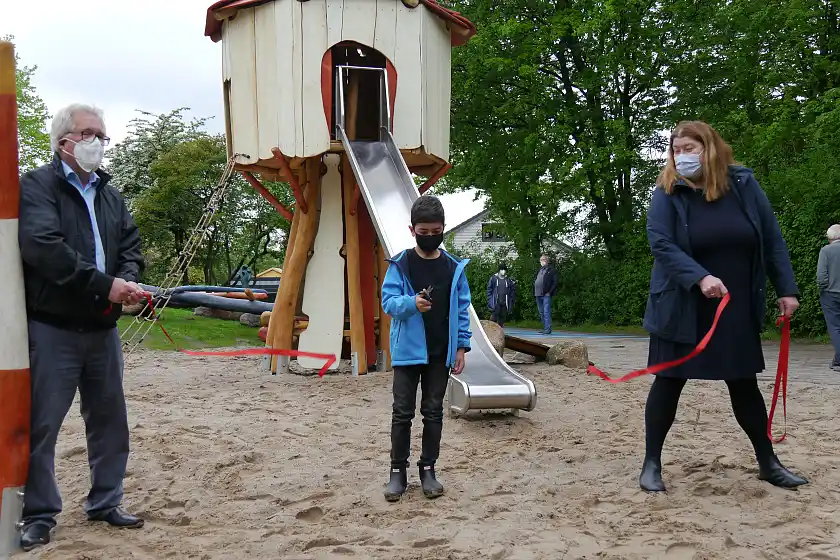 Mit dem Durchschneiden des Bandes eröffnet Elias (6) feierlich den neugestalteten Spielplatz am Blanken Hans. Holger Witzig (GOFUS e.V.) und Sozialsenatorin Anja Stahmann assistieren. 
